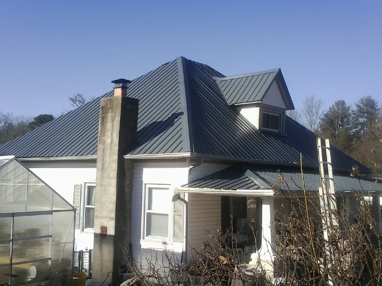 Dark blue standing seam metal roof on a white farmhouse with dormer — Slate & Tile Roof Repair by Roofing Brothers in Chicago Heights