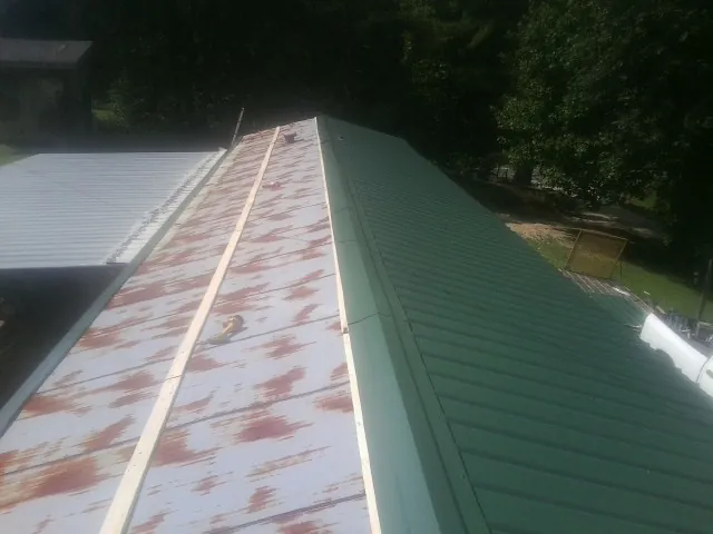 Old rusted panels beside newly installed green metal roofing — Wind Damage Roof Repair by Roofing Brothers in Chicago Heights
