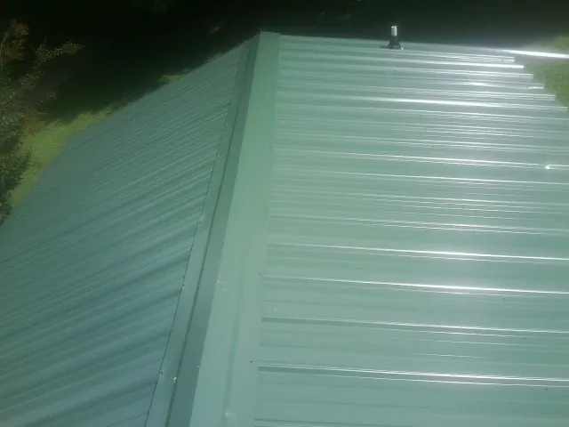 New green metal panels meeting at the ridge of a roof — Flat Roof Repair work by our crew in Chicago Heights