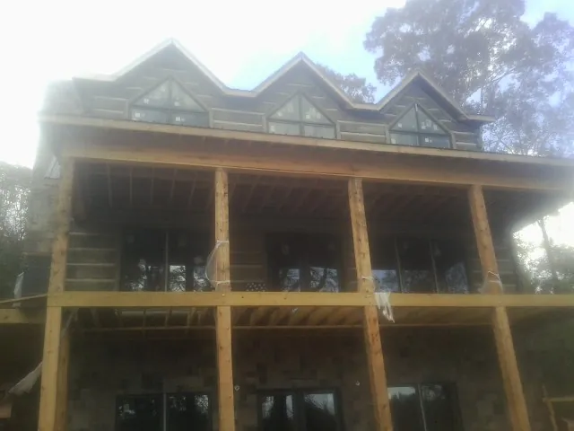 Dormers and porch framing on a large log home under construction — Roof Coating work by our crew in Chicago Heights