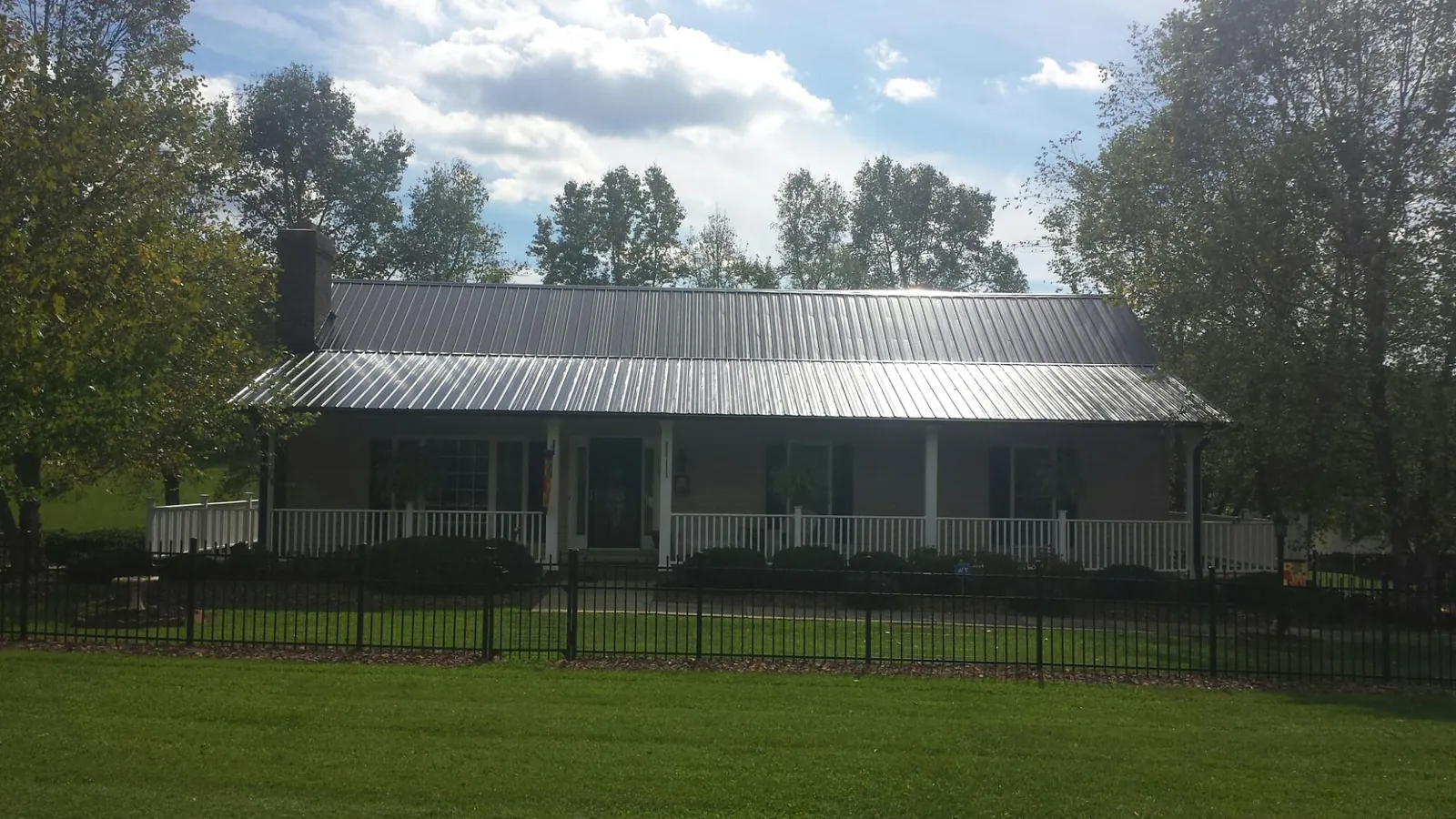 Gray metal roof on a brick ranch with a full width front porch — Gutter Guard Installation work by our crew in Chicago Heights