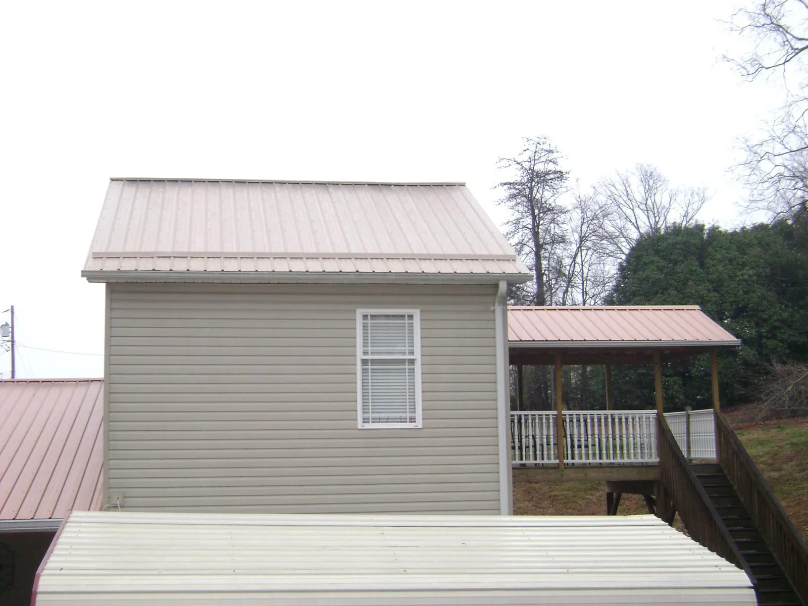 Tan metal roofs on a two story addition and attached porch, from a Roof Replacement job in Chicago Heights