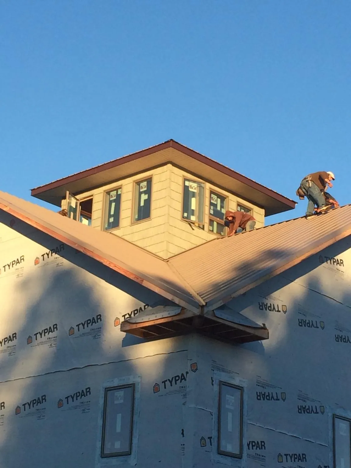 Roofers working around a rooftop cupola on a new metal roof at sunset — Roof Waterproofing in Chicago Heights by Roofing Brothers